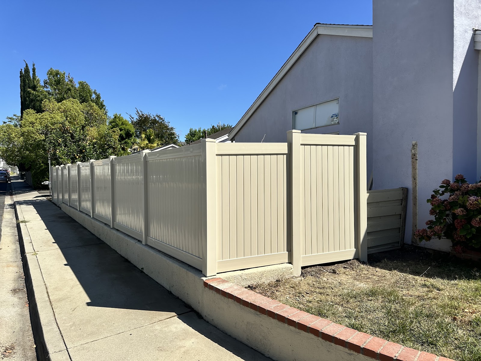Tan vinyl fence running along a driveway